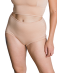Woman wearing an ada light nude organic cotton high rise brief bottom on a white background