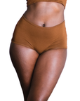 Woman wearing an ella deep nude high rise organic cotton brief bottom on a white background, front