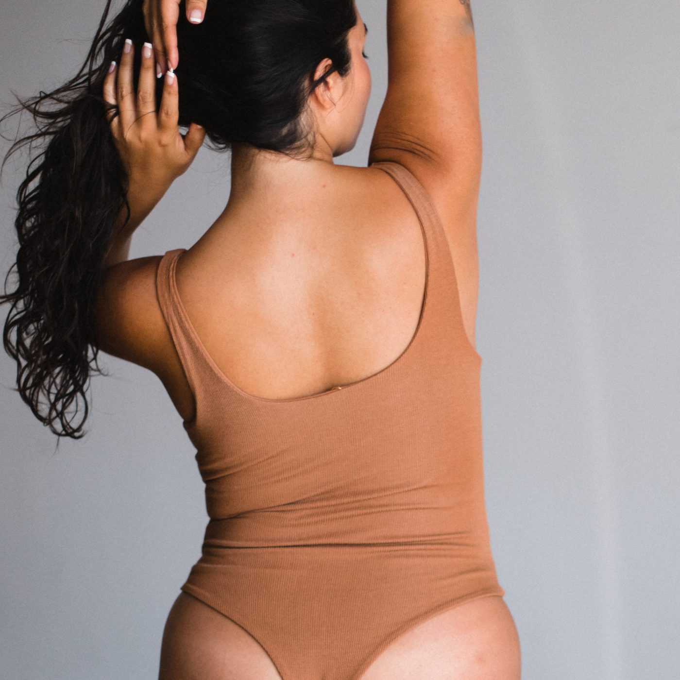 Back view of bodysuit, thong style. Maya nude color, a caramel tone.