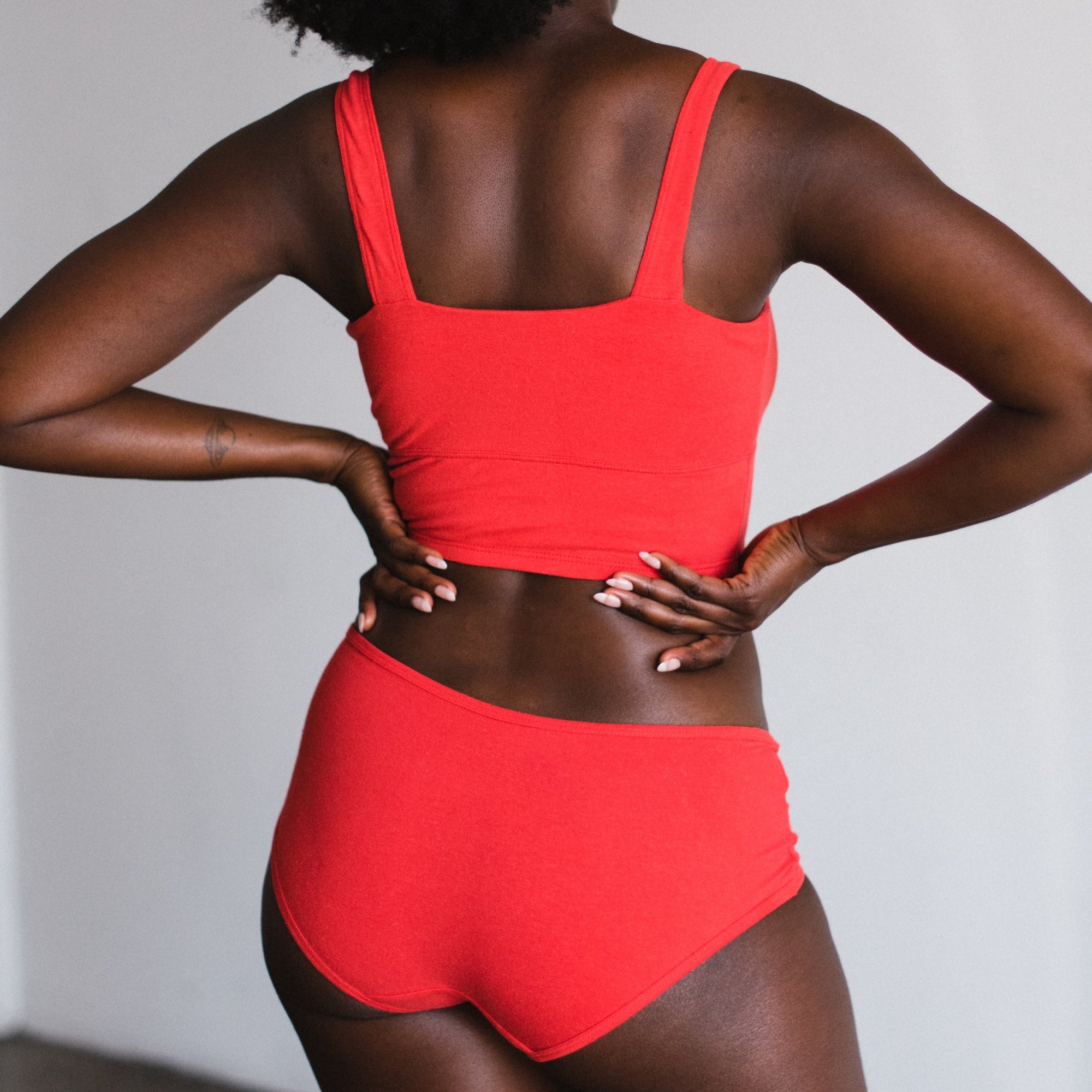 back view, model on hips in square neck bralette and mid rise briefs in poppy