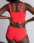 back view, model on hips in square neck bralette and mid rise briefs in poppy